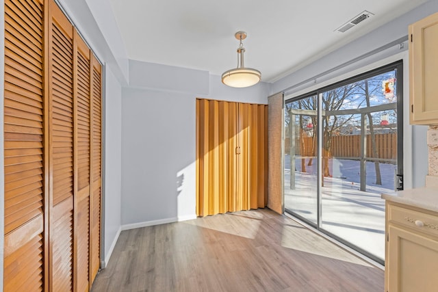 unfurnished dining area featuring baseboards, visible vents, and light wood-style floors