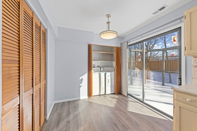 unfurnished dining area with light wood-style floors, baseboards, visible vents, and washer and dryer