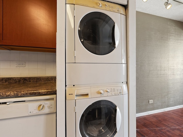 laundry room featuring a textured ceiling, laundry area, baseboards, dark wood finished floors, and stacked washer and clothes dryer