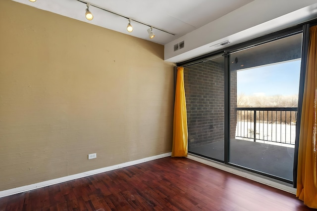 spare room featuring dark wood finished floors, visible vents, and baseboards