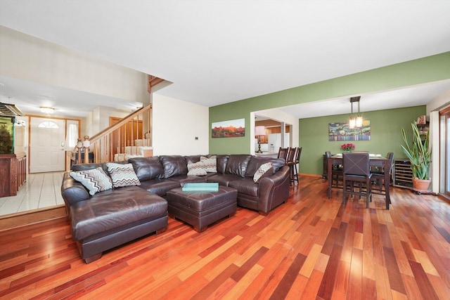 living area with a chandelier, stairway, and light wood-style flooring