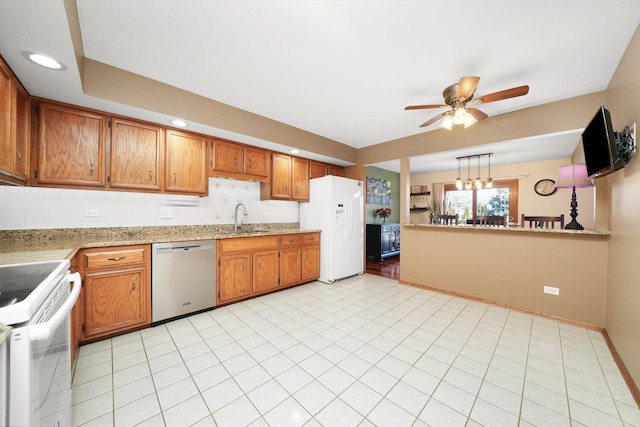 kitchen featuring brown cabinetry, white appliances, a sink, and tasteful backsplash