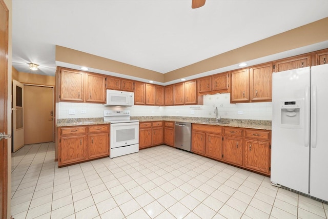 kitchen featuring white appliances, decorative backsplash, brown cabinetry, and a sink