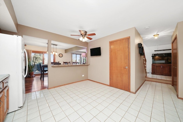 interior space with light countertops, light tile patterned flooring, freestanding refrigerator, and baseboards