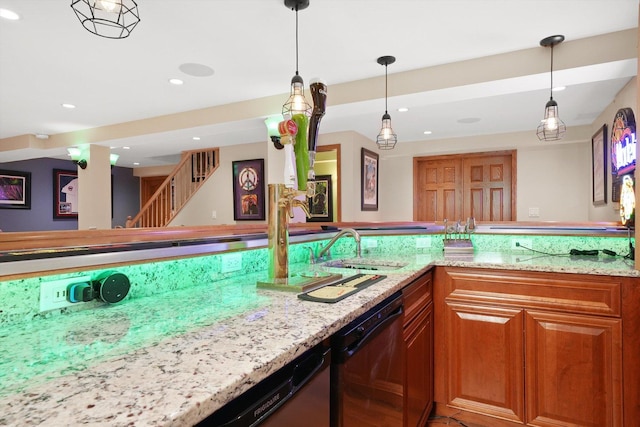 kitchen featuring hanging light fixtures, brown cabinetry, a sink, light stone countertops, and dishwasher