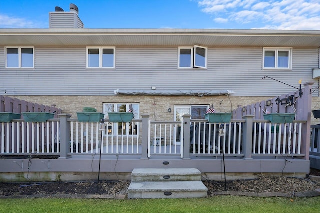 back of property with a chimney and a wooden deck