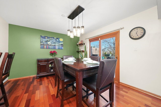 dining room featuring a chandelier, baseboards, and wood finished floors