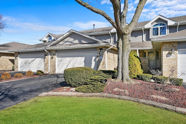 view of front of house featuring driveway, brick siding, a front lawn, and an attached garage