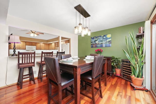 dining room featuring light wood-type flooring and ceiling fan with notable chandelier