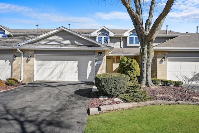 view of front facade featuring brick siding, an attached garage, and aphalt driveway