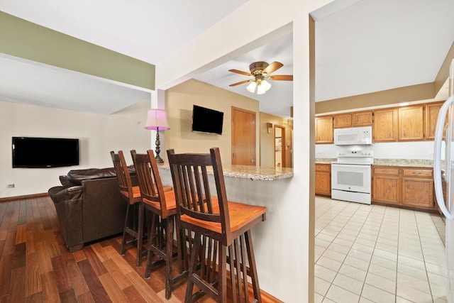 kitchen featuring brown cabinets, light wood-style floors, open floor plan, ceiling fan, and white appliances