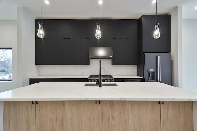 kitchen with a kitchen island with sink, light brown cabinetry, high quality fridge, and decorative light fixtures