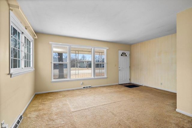 spare room featuring carpet floors, visible vents, and baseboards