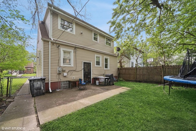 back of property featuring a yard, a trampoline, and a patio area