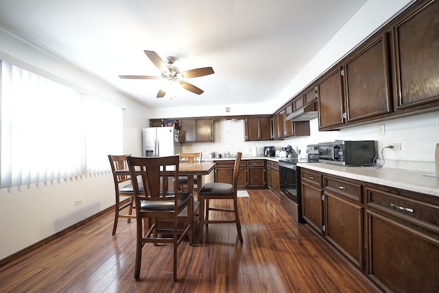 kitchen featuring appliances with stainless steel finishes, tasteful backsplash, dark brown cabinetry, ceiling fan, and dark hardwood / wood-style floors