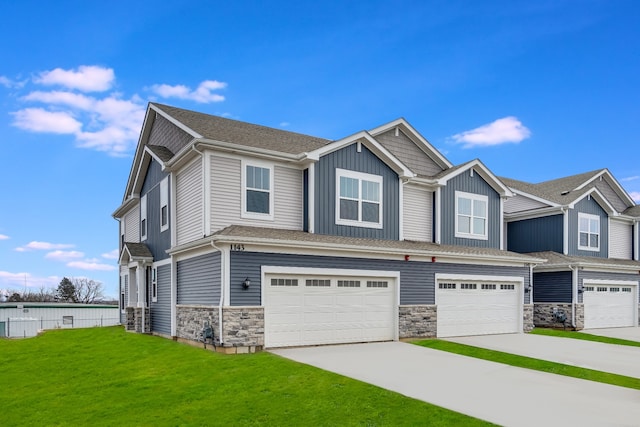 view of front of home featuring an attached garage, stone siding, driveway, and a front lawn