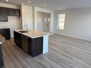 kitchen featuring stainless steel dishwasher, light hardwood / wood-style floors, and a kitchen island with sink