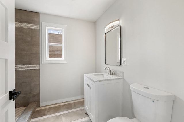 bathroom with tile patterned floors, toilet, tiled shower, vanity, and baseboards