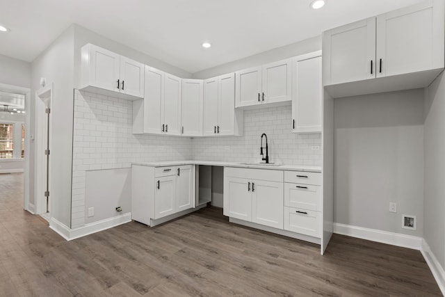 kitchen with white cabinetry, light countertops, baseboards, a sink, and dark wood-style floors