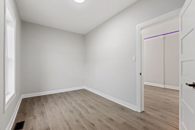 empty room featuring wood finished floors, baseboards, and visible vents
