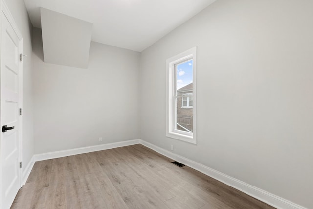 empty room with baseboards, visible vents, and light wood-type flooring