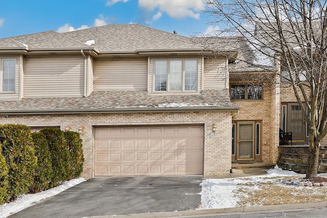 view of front of home with a garage, a shingled roof, brick siding, and aphalt driveway