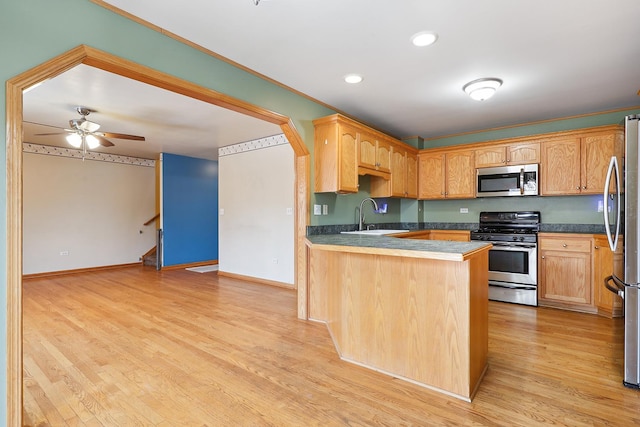 kitchen with stainless steel appliances, a sink, light wood-type flooring, a peninsula, and baseboards