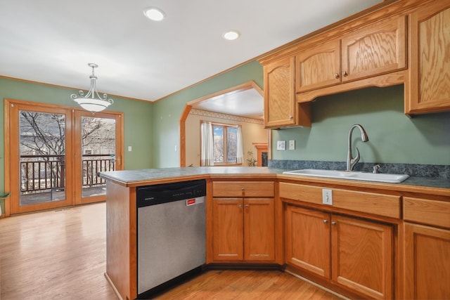 kitchen with pendant lighting, crown molding, light wood finished floors, stainless steel dishwasher, and a sink