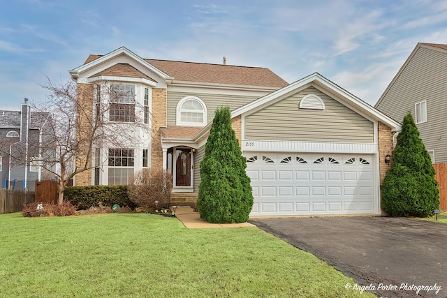 traditional-style house featuring brick siding, driveway, a front lawn, and fence