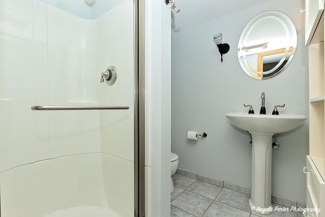 full bathroom featuring toilet, a shower stall, baseboards, and tile patterned flooring