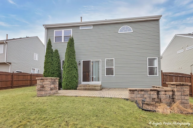 rear view of property featuring entry steps, a patio, a lawn, and fence