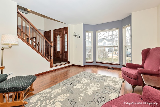 entrance foyer featuring visible vents, stairway, baseboards, and wood finished floors