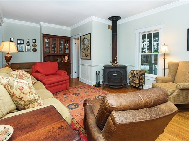 44W906 Berner Rd, Hampshire, IL 60140 - living room featuring ornamental molding, wainscoting, wood finished floors, and a wood stove