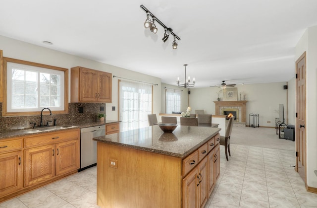 kitchen with a center island, dishwasher, pendant lighting, a brick fireplace, and sink