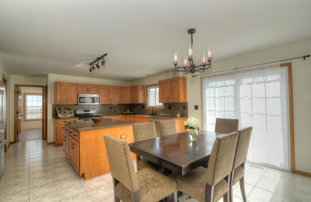 kitchen featuring backsplash, a chandelier, a kitchen island, appliances with stainless steel finishes, and hanging light fixtures