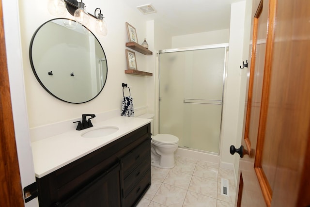 bathroom with toilet, vanity, and a shower with shower door