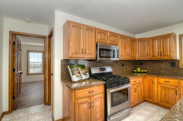 kitchen with tasteful backsplash, dark stone countertops, and appliances with stainless steel finishes