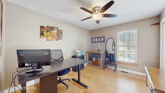 office space featuring light wood-style floors, baseboards, visible vents, and a ceiling fan