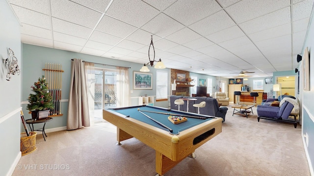 recreation room featuring carpet floors, a drop ceiling, a fireplace, and baseboards