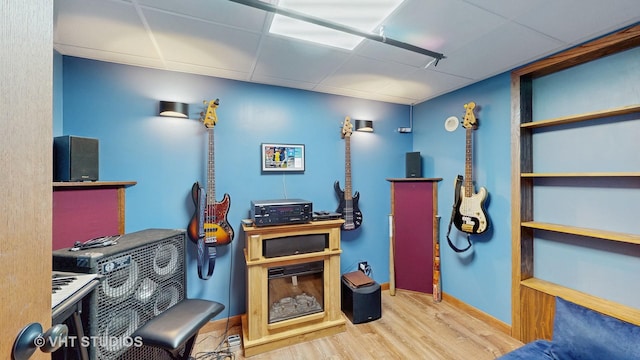 interior space with wood finished floors, a paneled ceiling, and baseboards