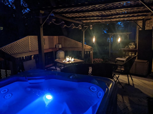 pool at night featuring an outdoor hot tub and a fire pit