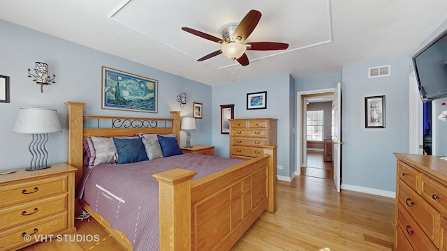 bedroom with ceiling fan, light wood-style flooring, visible vents, and baseboards