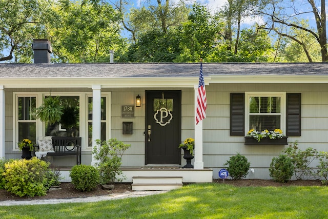 property entrance featuring roof with shingles, a porch, and a chimney