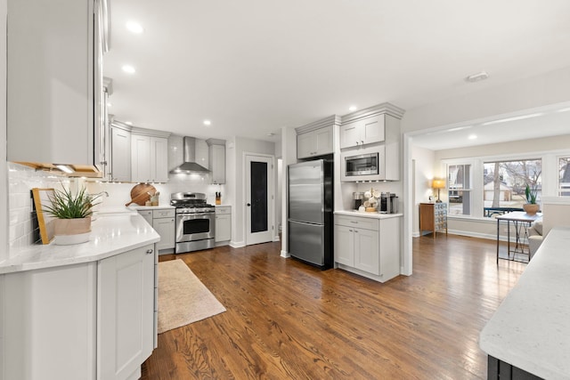 kitchen with recessed lighting, stainless steel appliances, wall chimney exhaust hood, tasteful backsplash, and dark wood finished floors