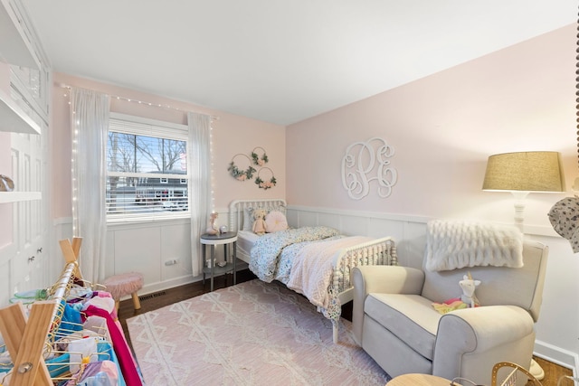 bedroom featuring a wainscoted wall and wood finished floors