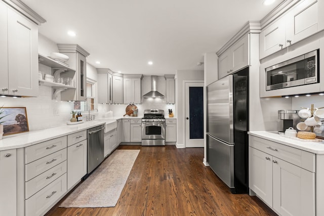 kitchen featuring dark wood-style floors, stainless steel appliances, wall chimney range hood, and backsplash