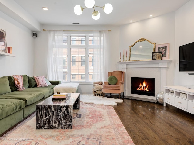 living area with a warm lit fireplace, visible vents, wood finished floors, and recessed lighting