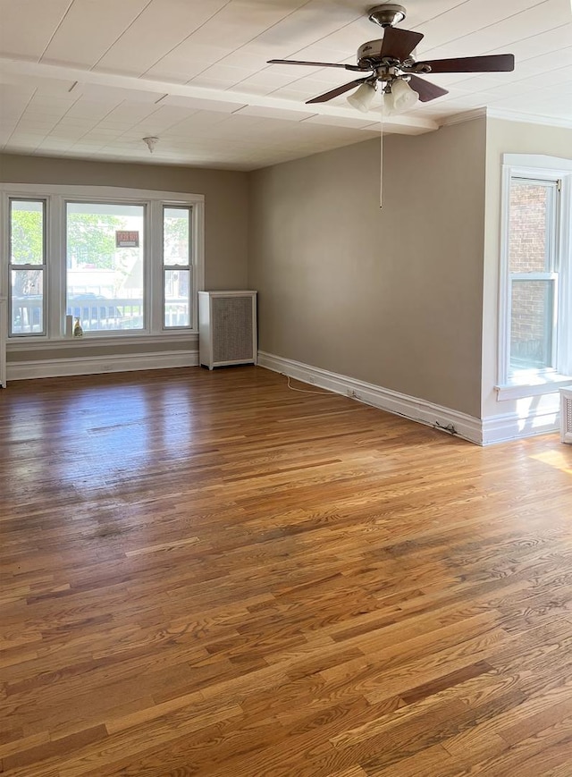 empty room featuring ceiling fan, wood finished floors, and baseboards