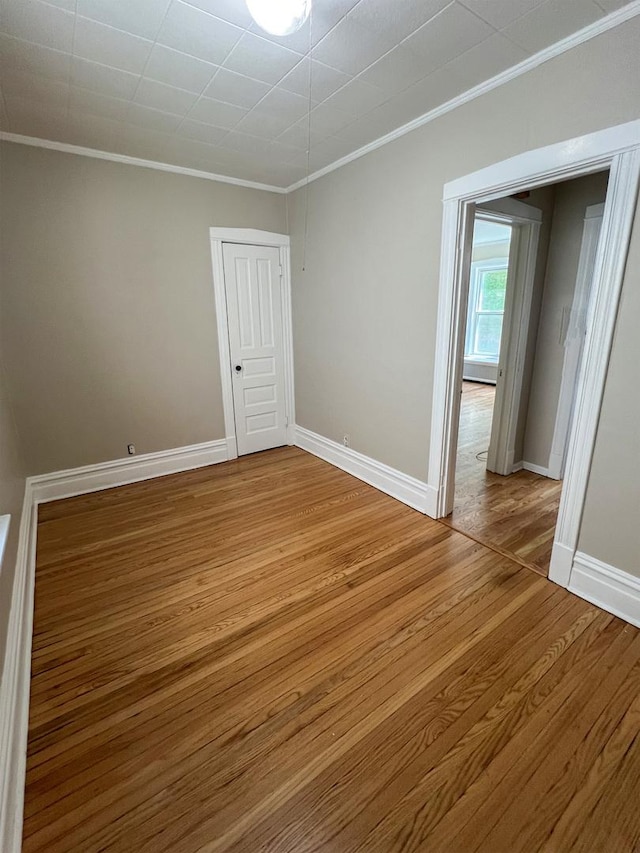 spare room with ornamental molding, wood finished floors, and baseboards