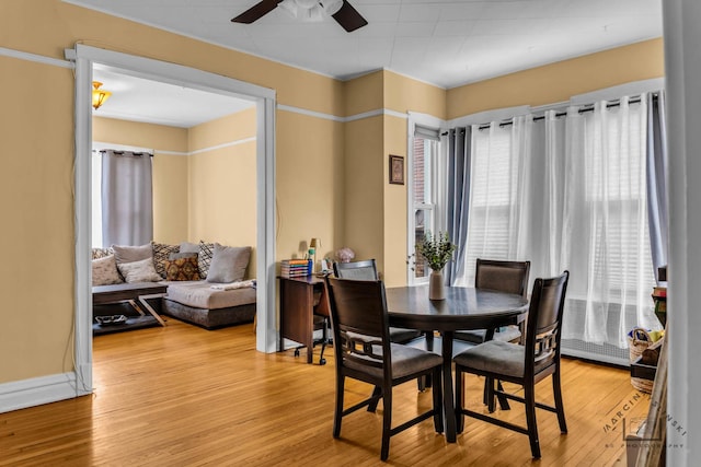 dining room with light wood-style floors, ceiling fan, and baseboards